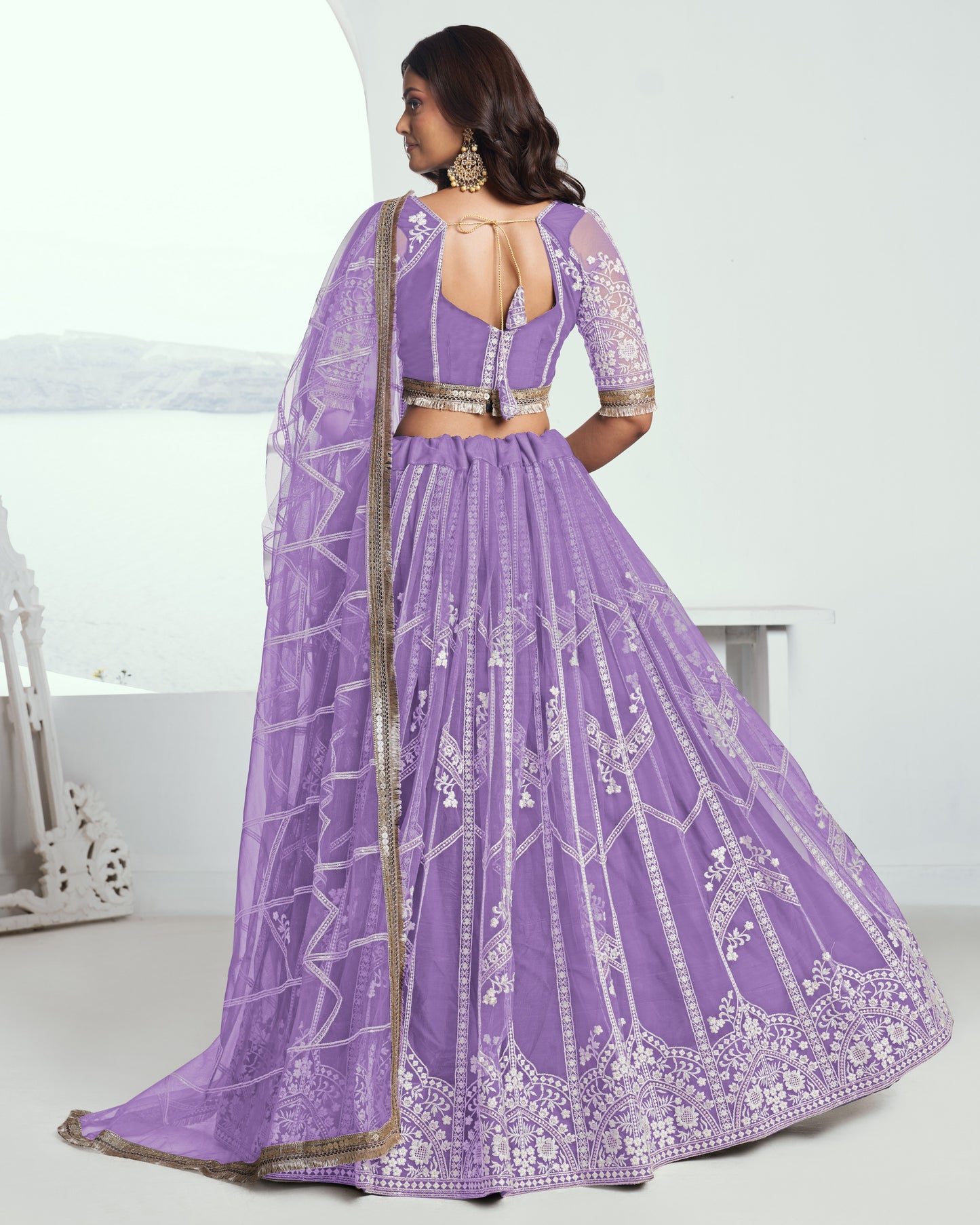 Woman wearing a purple embroidered lehenga with a white background