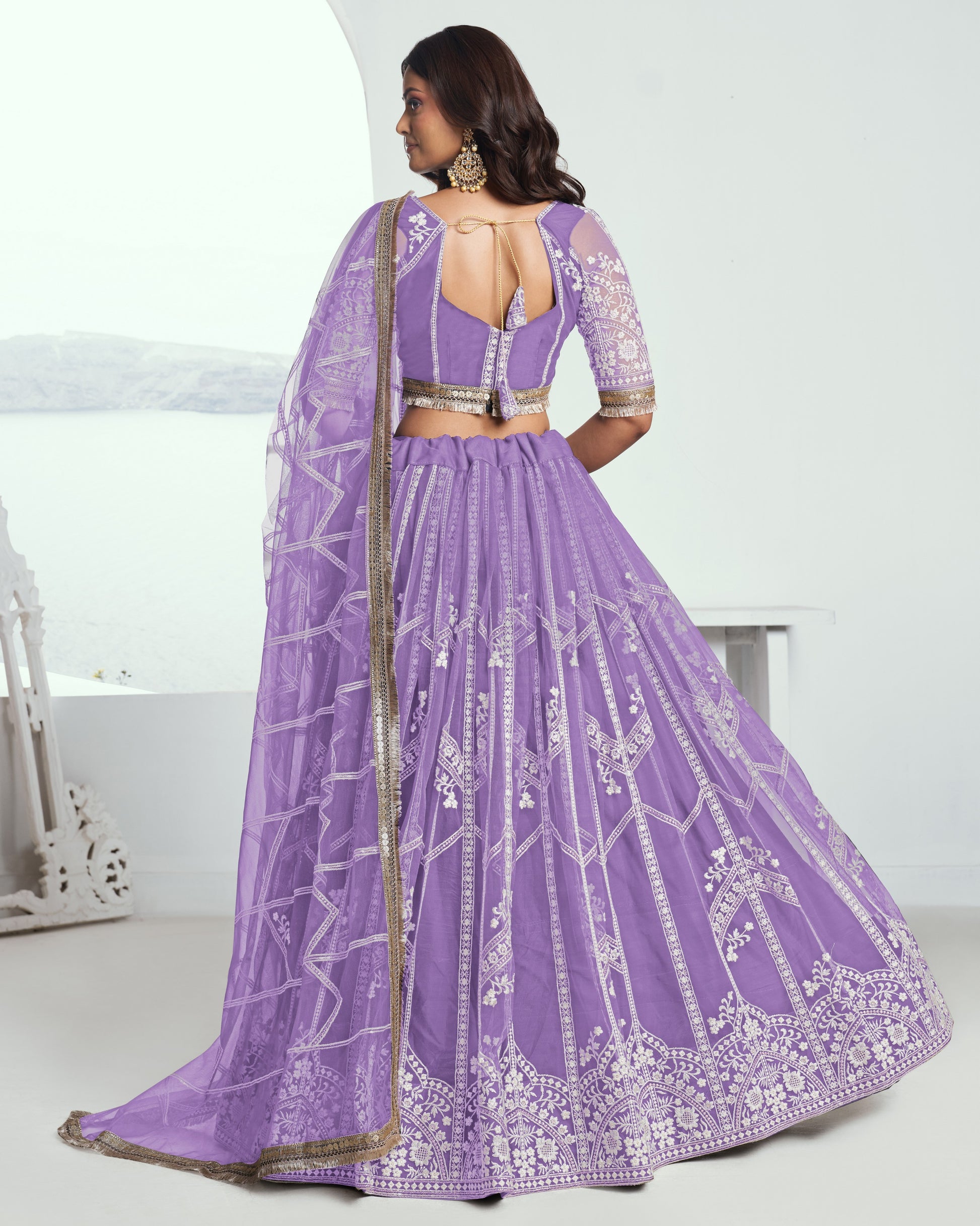 Woman wearing a purple embroidered lehenga with a white background