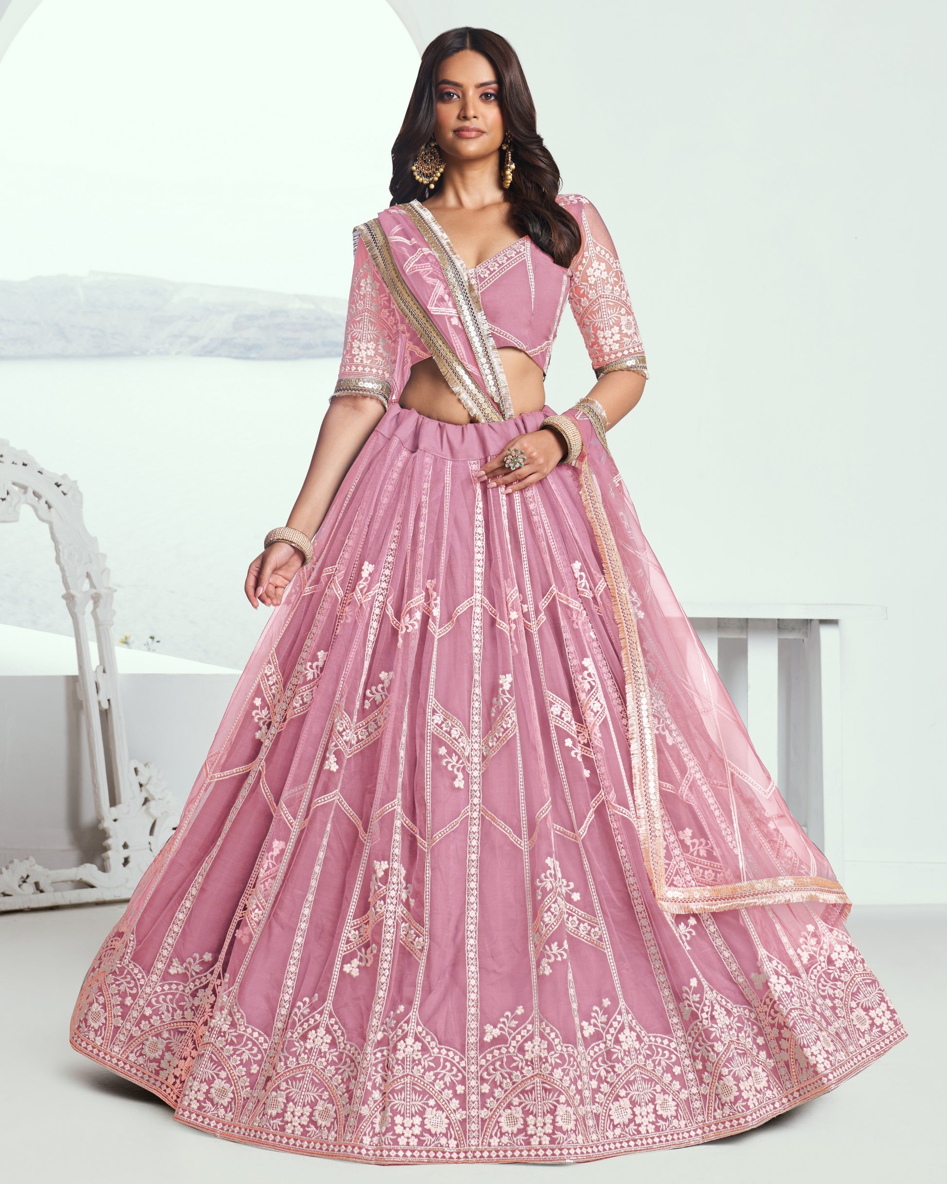 Woman wearing a pink embroidered traditional outfit on a white background