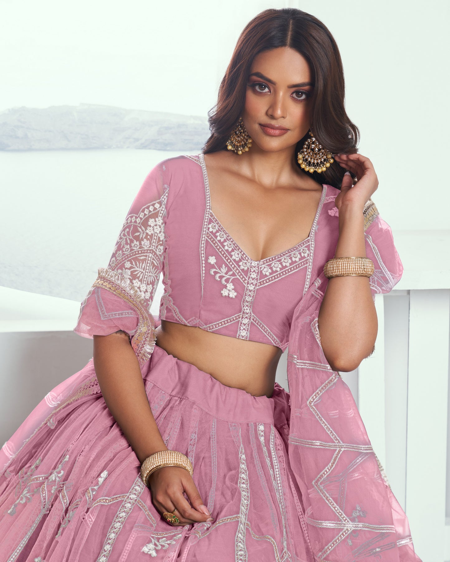Woman wearing a pink traditional outfit with white embroidery on a white background
