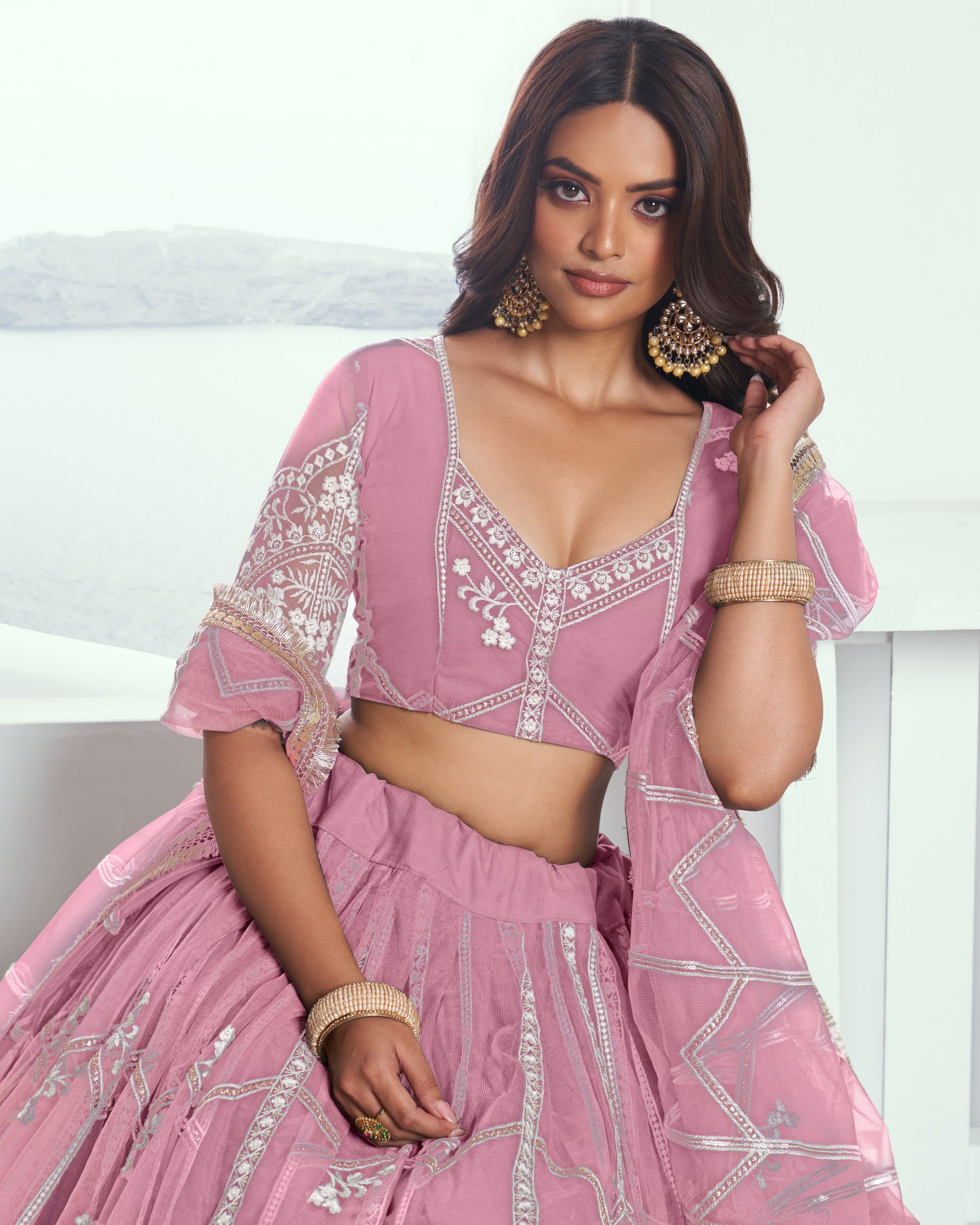 Woman wearing a pink traditional outfit with white embroidery on a white background