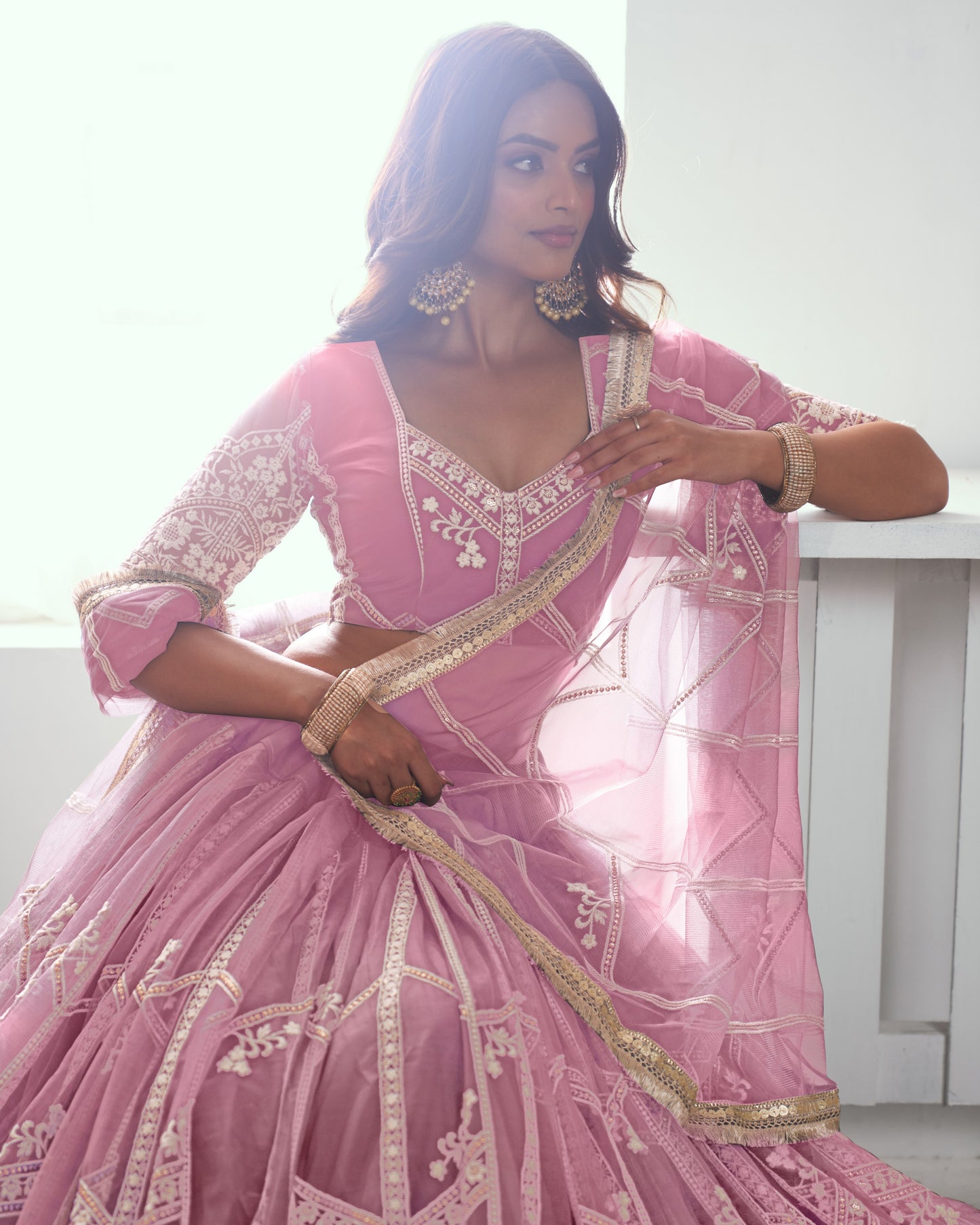 Woman wearing a pink embroidered traditional outfit with gold details.