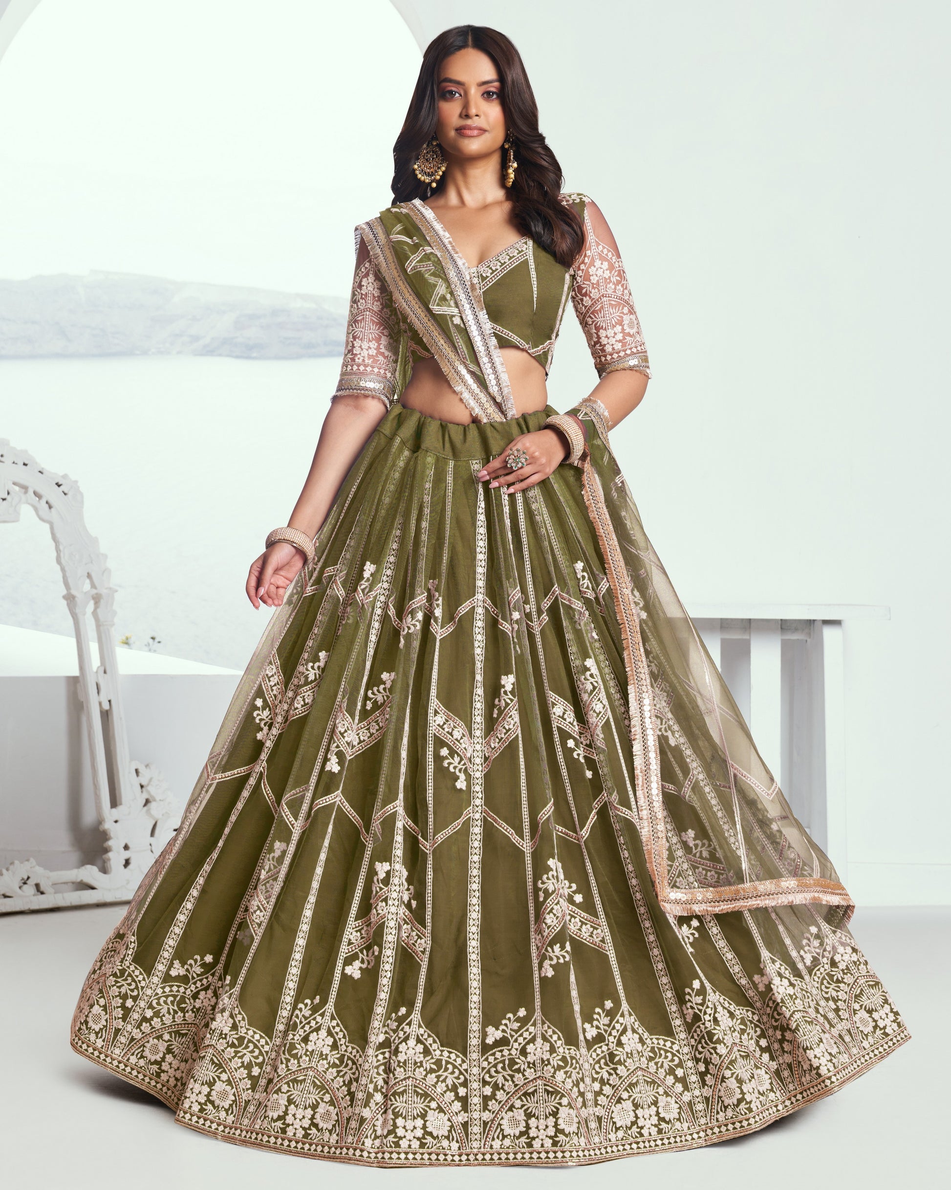 Woman wearing a green embroidered traditional outfit with a white background