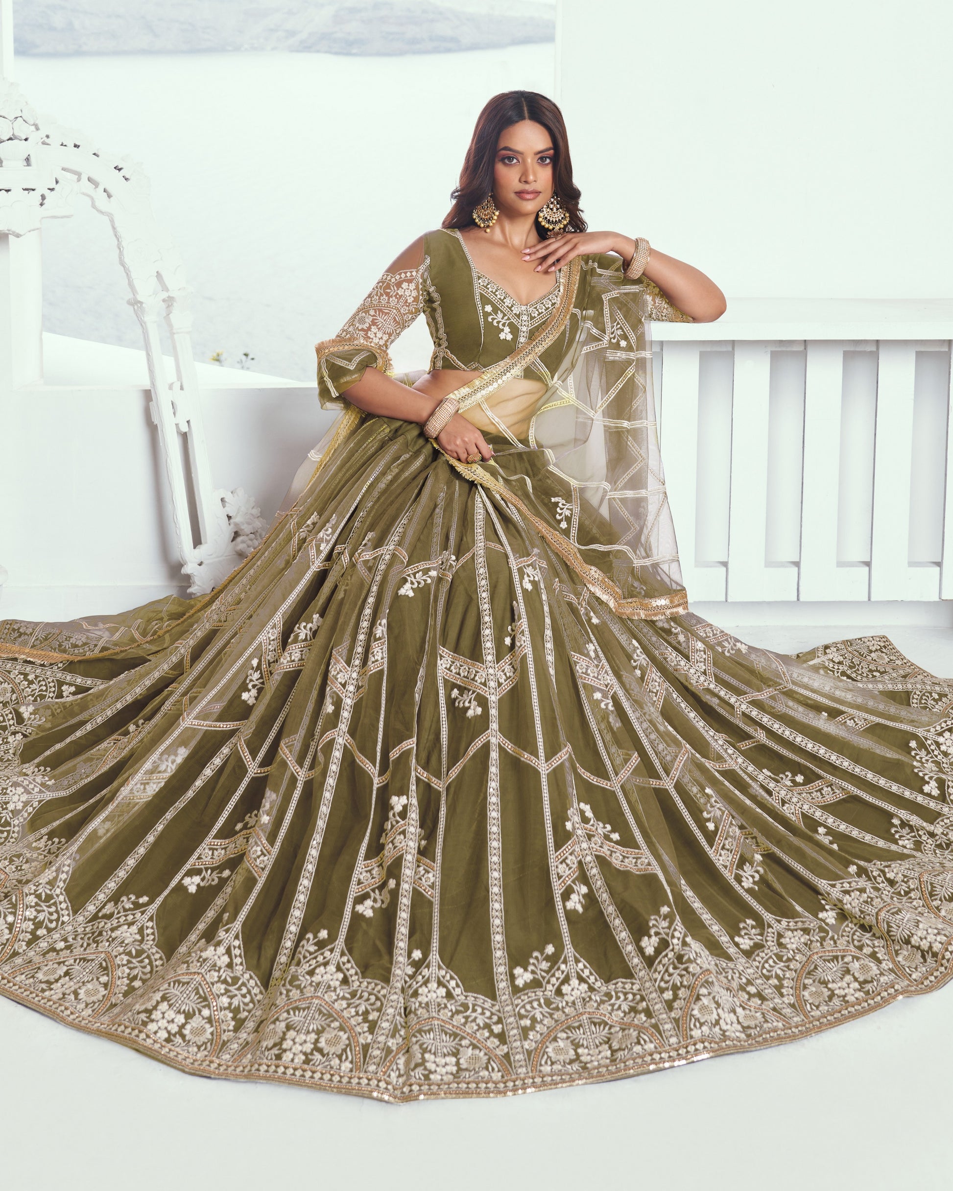 Woman wearing a green embroidered saree with a white background