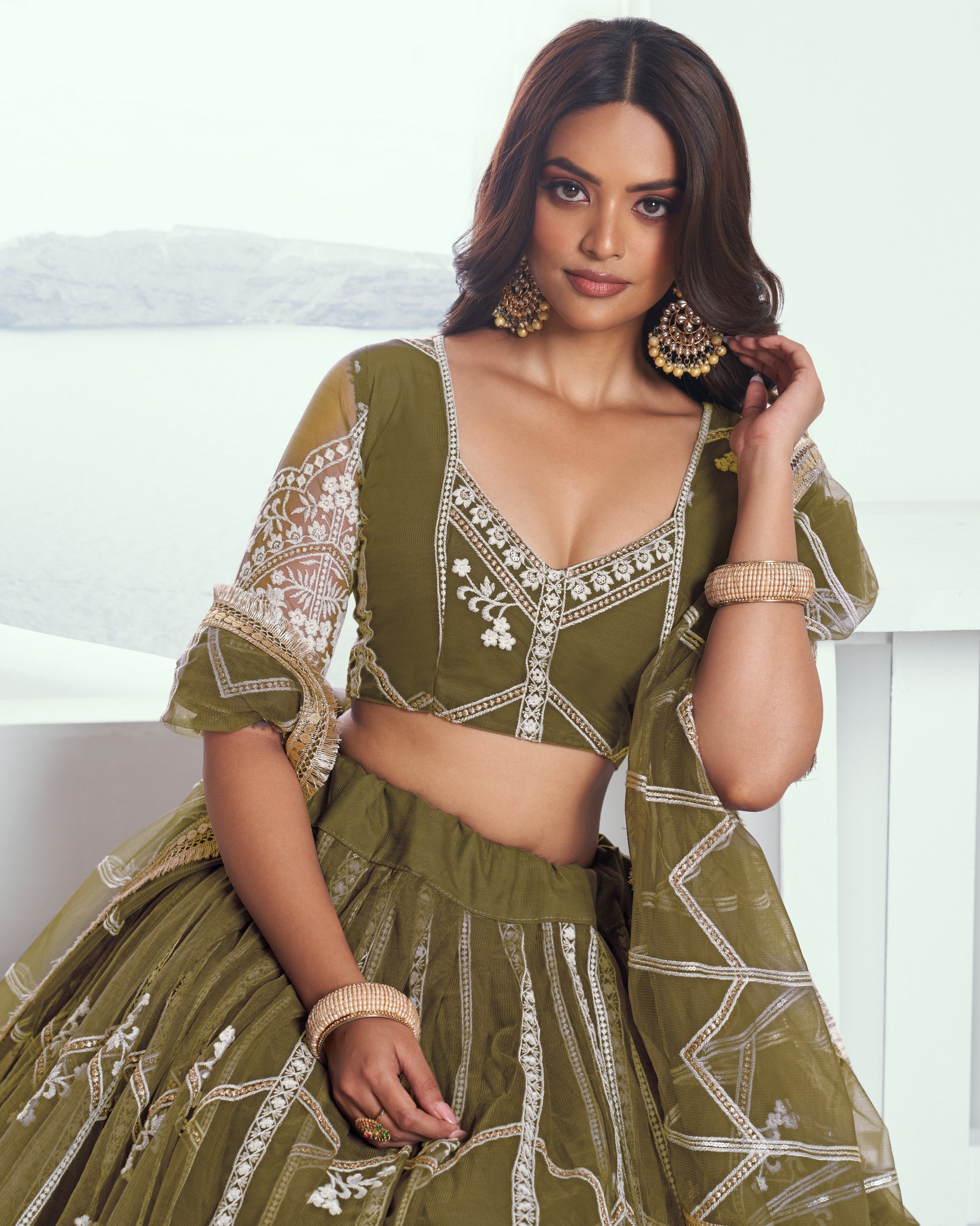 Woman wearing a green embroidered traditional outfit with white patterns on a white background