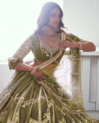 Woman wearing a green and gold traditional outfit with intricate designs.