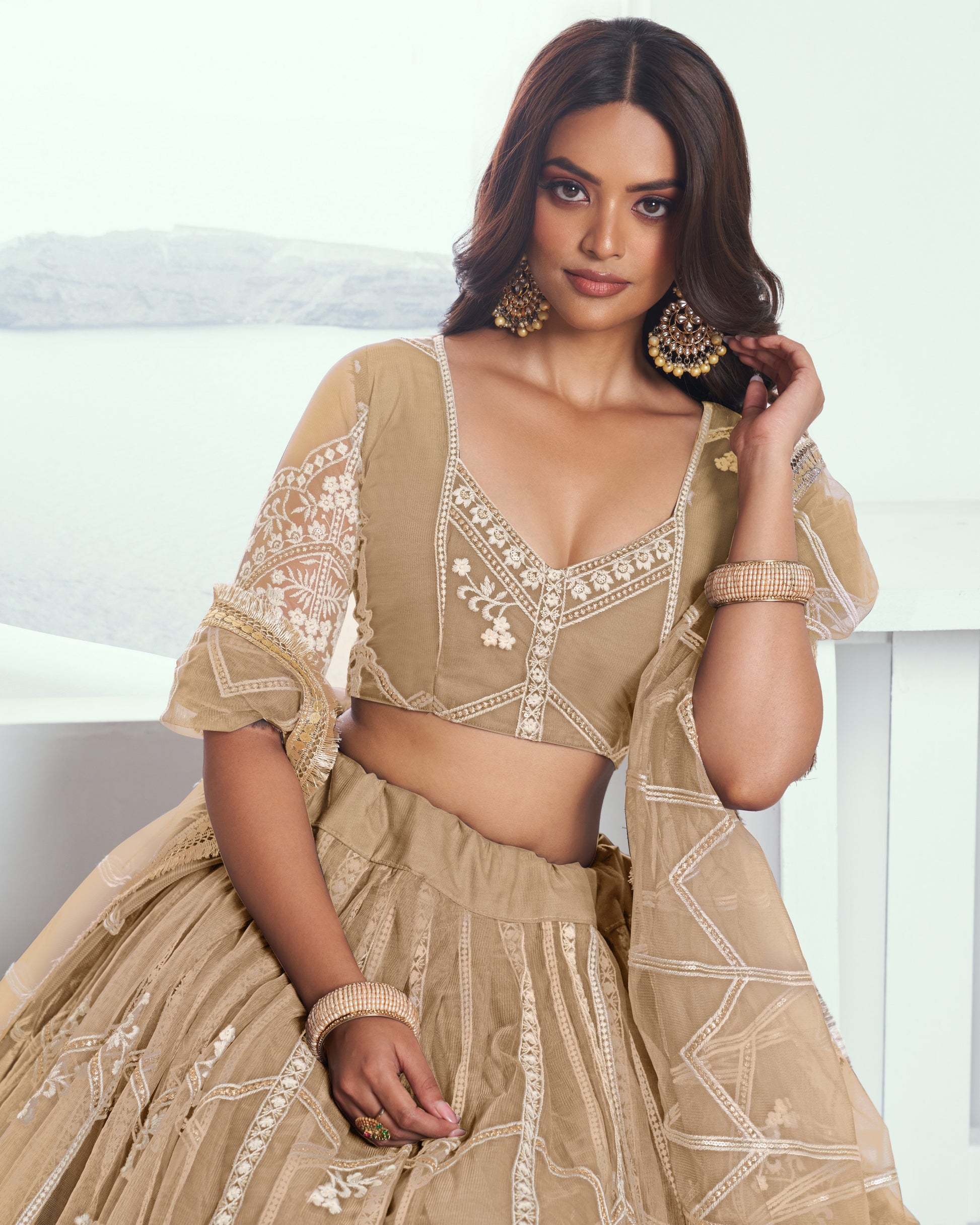 Woman wearing a beige embroidered traditional outfit with a white background