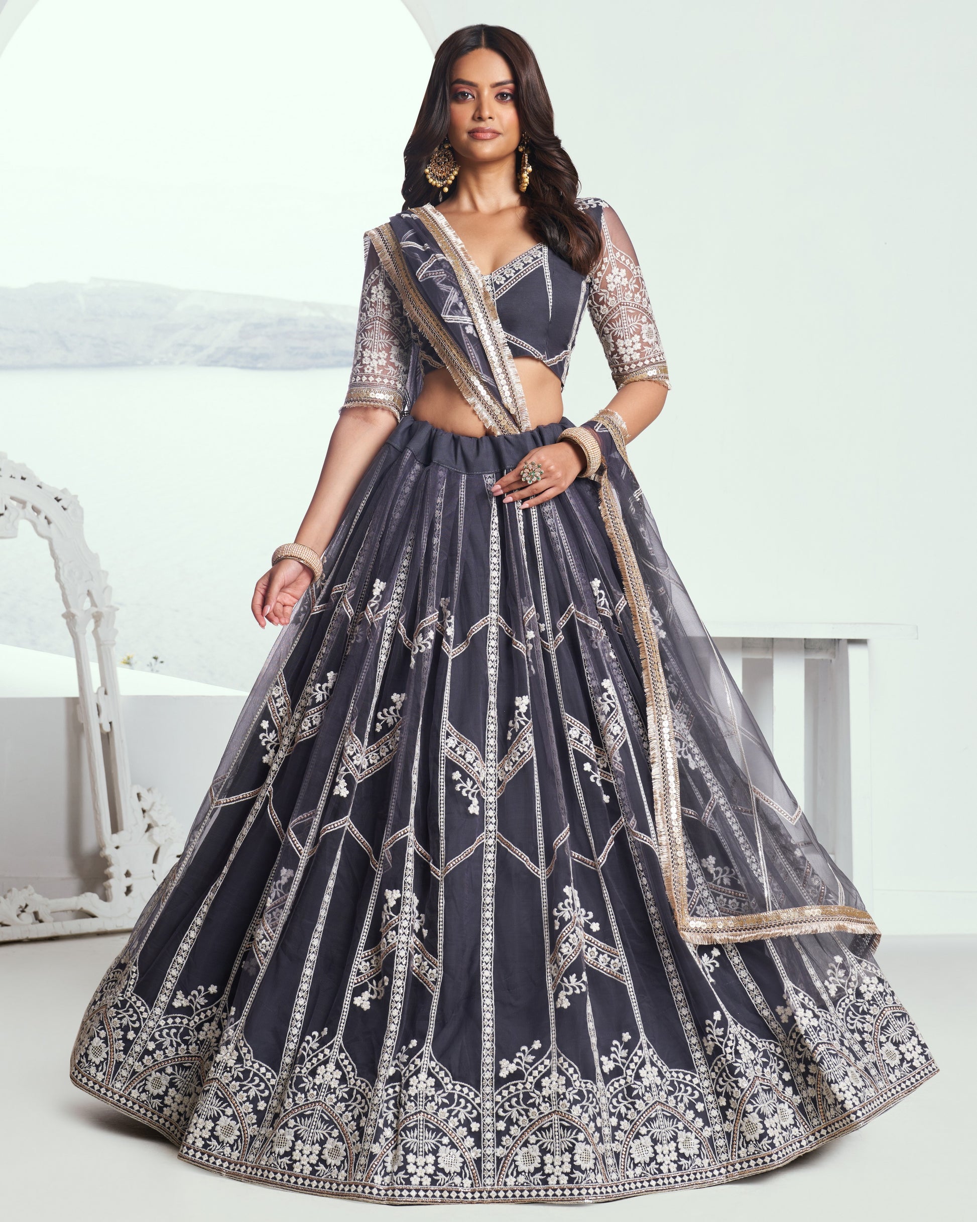 Woman wearing a dark blue embroidered lehenga with a white background