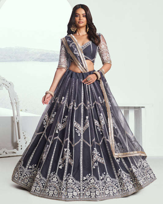 Woman wearing a dark blue embroidered lehenga with a white background