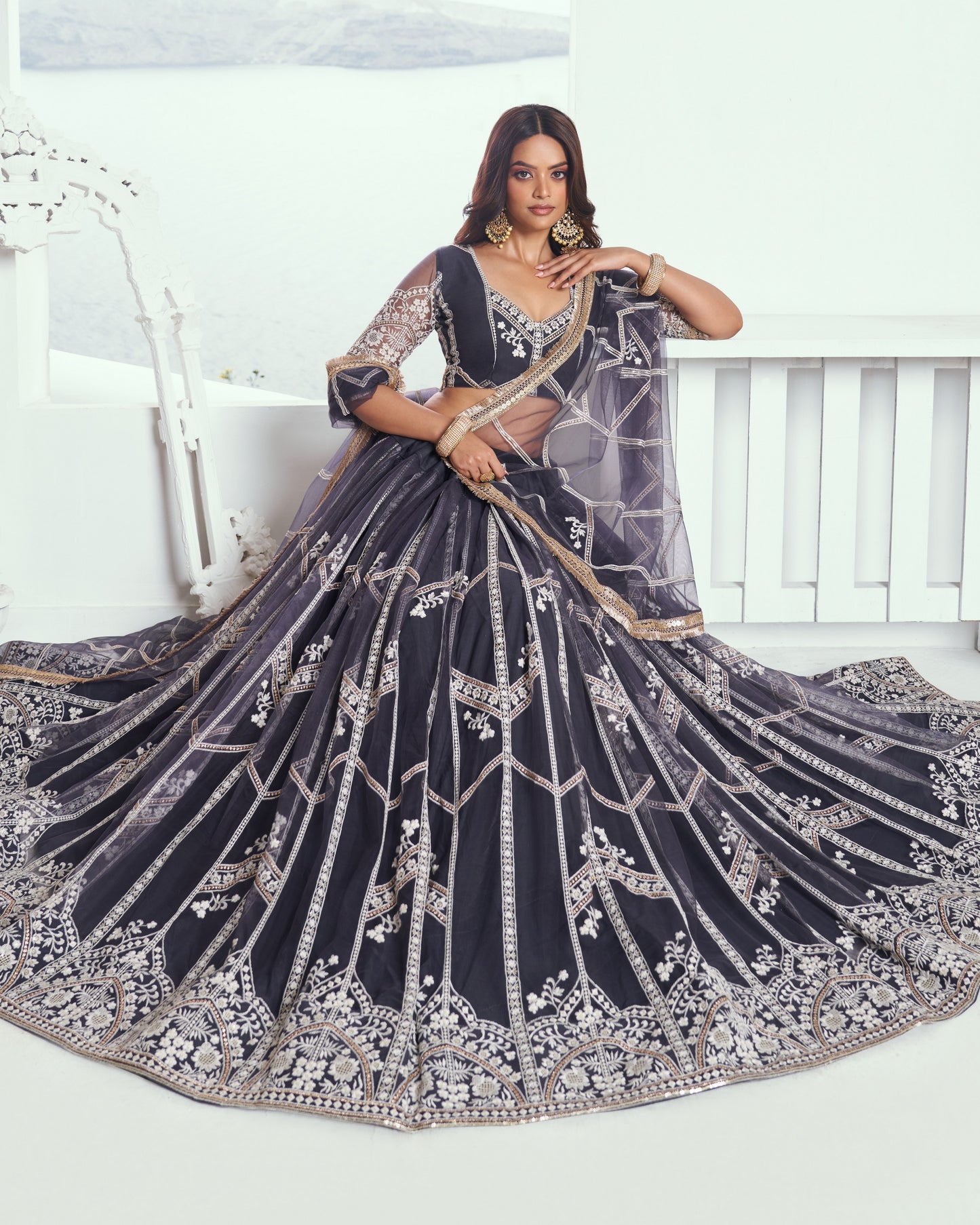 Woman in a dark blue embroidered lehenga with silver details on a white background