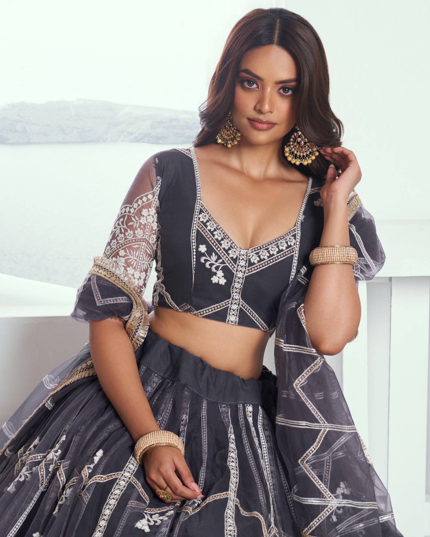 Woman wearing a dark blue embroidered traditional outfit with a white background