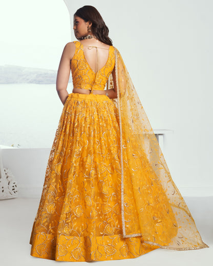 Woman wearing a yellow embroidered lehenga with a white background