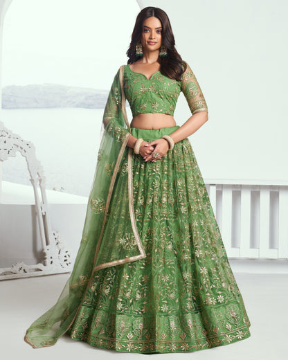 Woman wearing a green embroidered lehenga with a white background