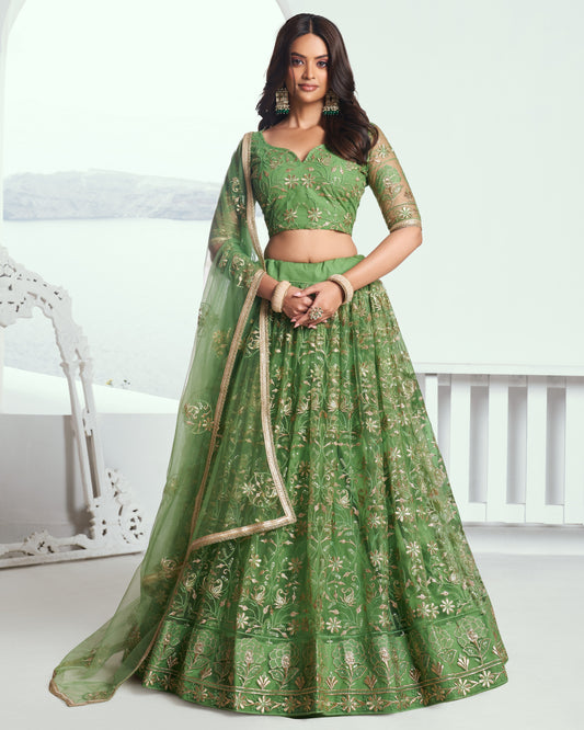 Woman wearing a green embroidered lehenga with a white background