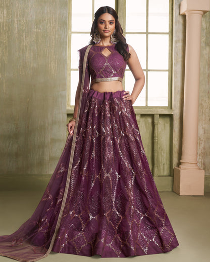 Woman wearing a purple traditional outfit with a matching dupatta in a room with large windows.
