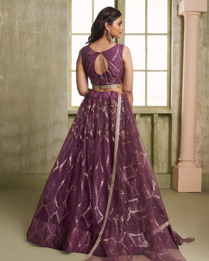 Woman wearing a purple evening gown with a geometric pattern in a room with large windows.