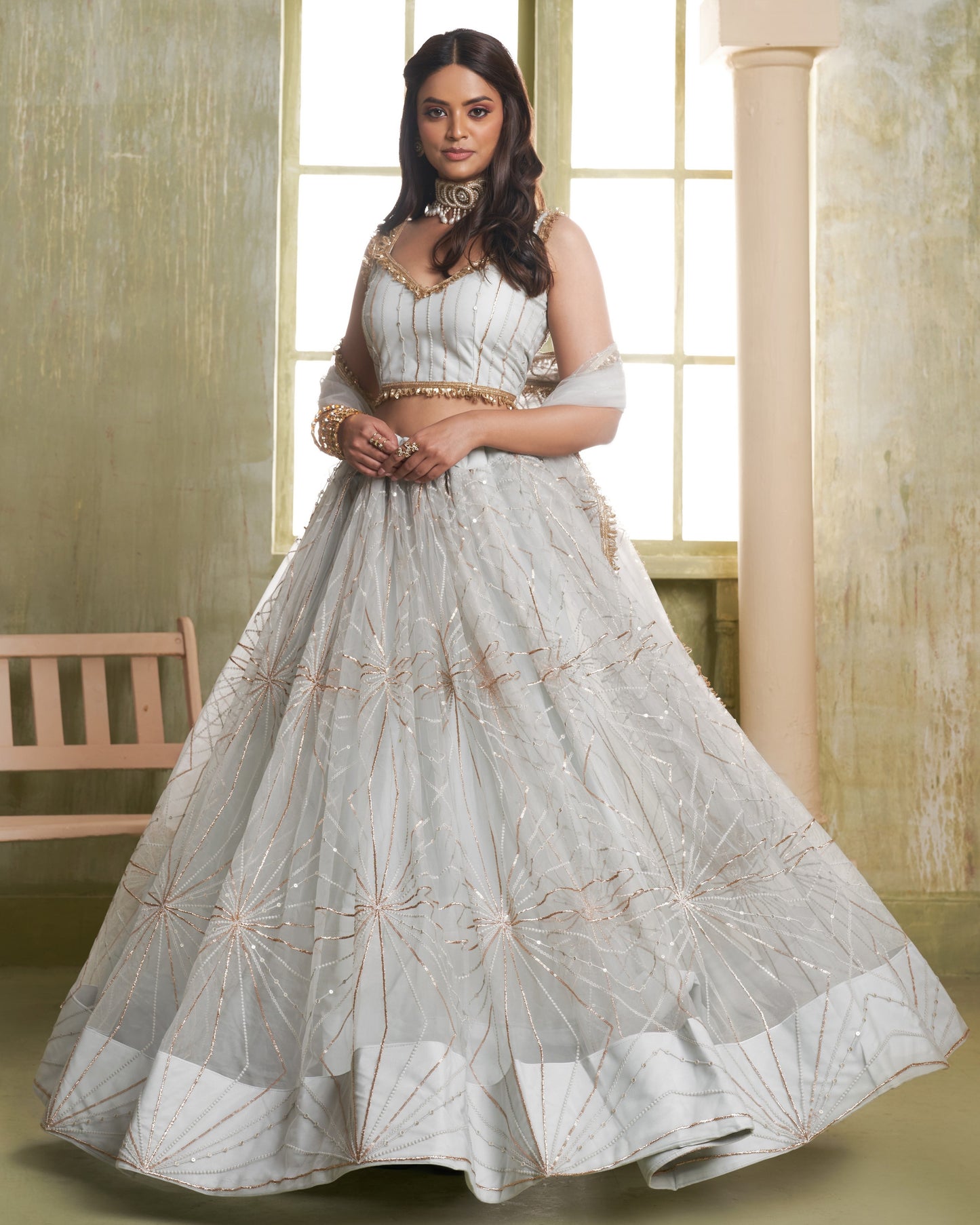 Woman wearing a white embroidered traditional outfit in a bright room.