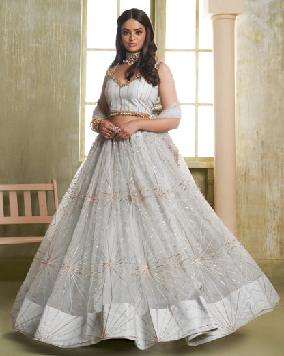 Woman wearing a white embroidered traditional outfit in a bright room.