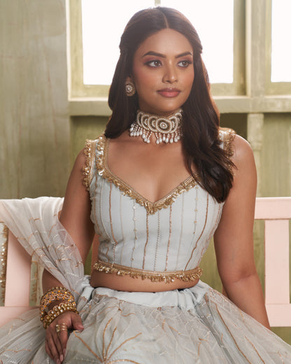 Woman in a traditional outfit with gold embroidery sitting on a couch.