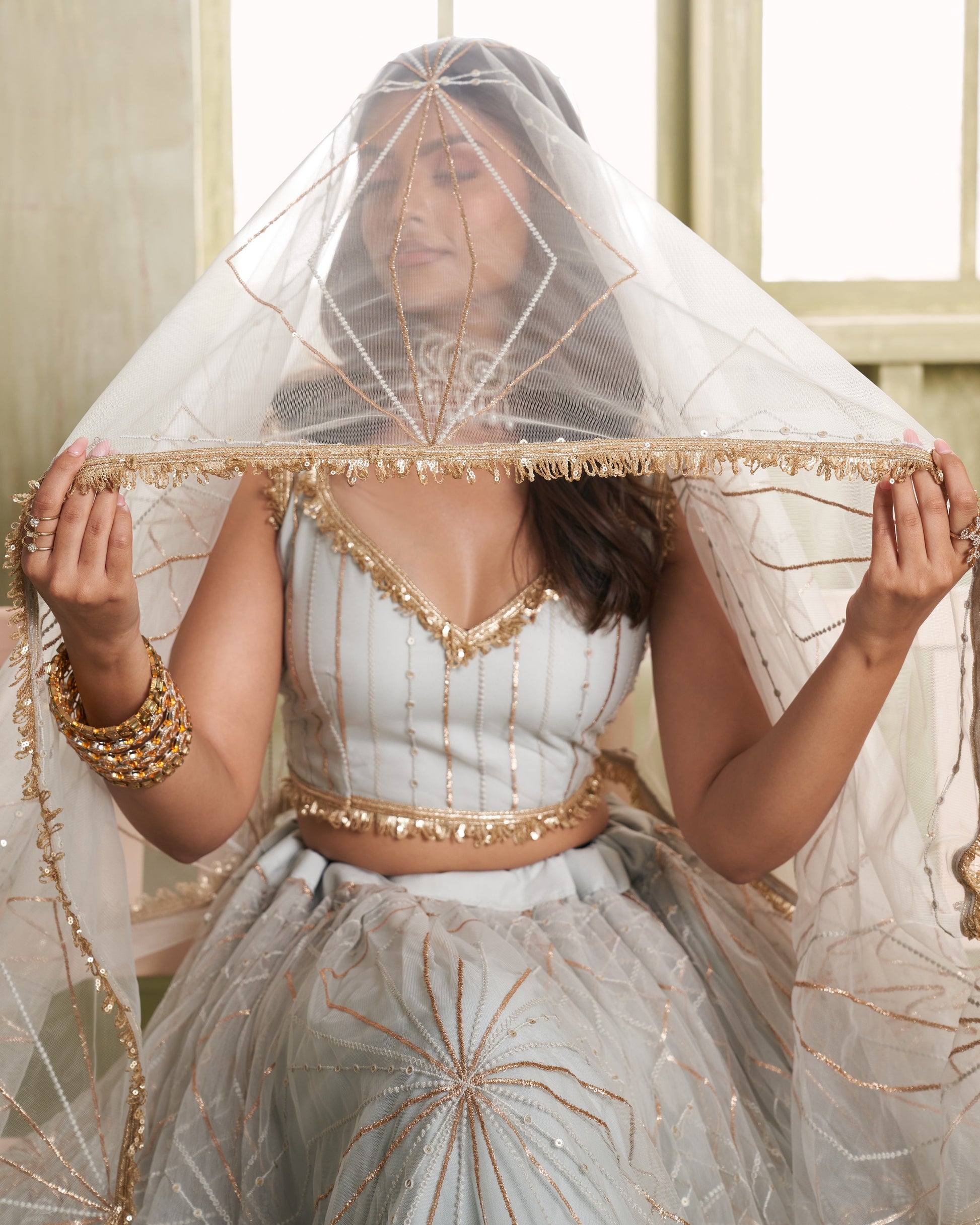 Woman wearing a traditional outfit with a decorative veil indoors