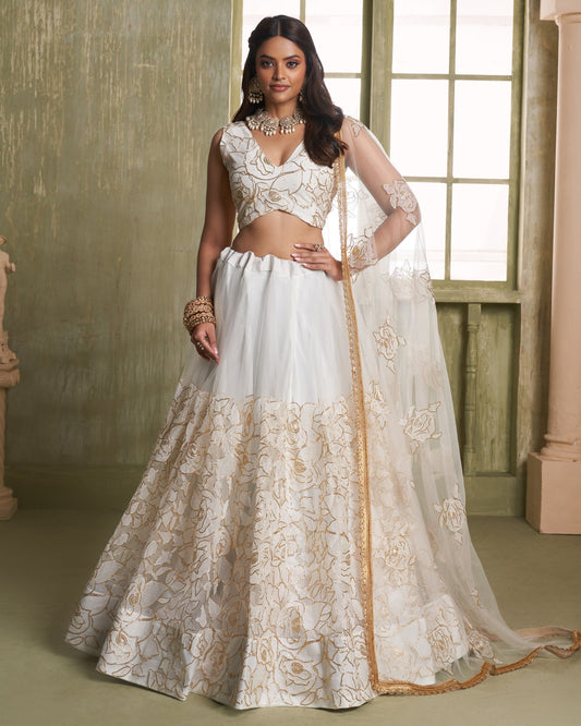 Woman wearing a white and gold embroidered traditional outfit indoors.