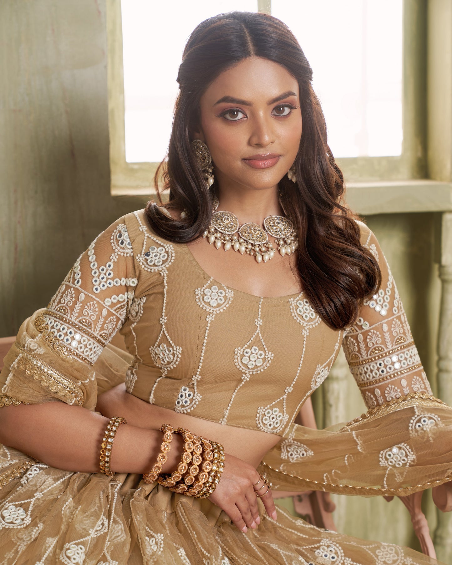 Woman wearing a traditional embroidered outfit with jewelry indoors.