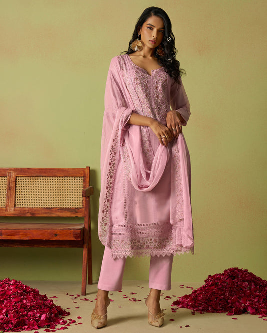 Woman in a pink traditional outfit with a matching dupatta on a green background