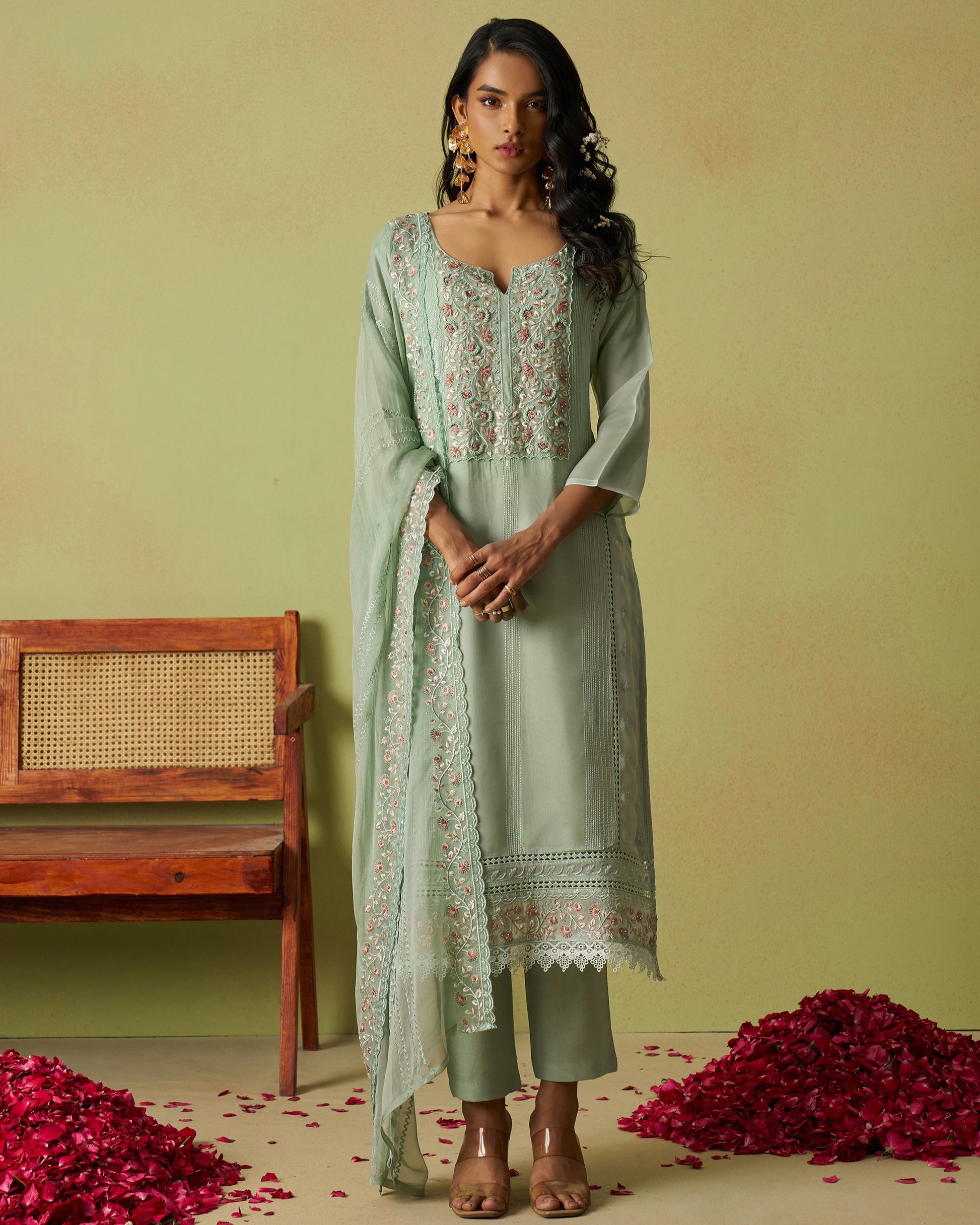 Woman in a light green traditional outfit with floral patterns on a yellow background