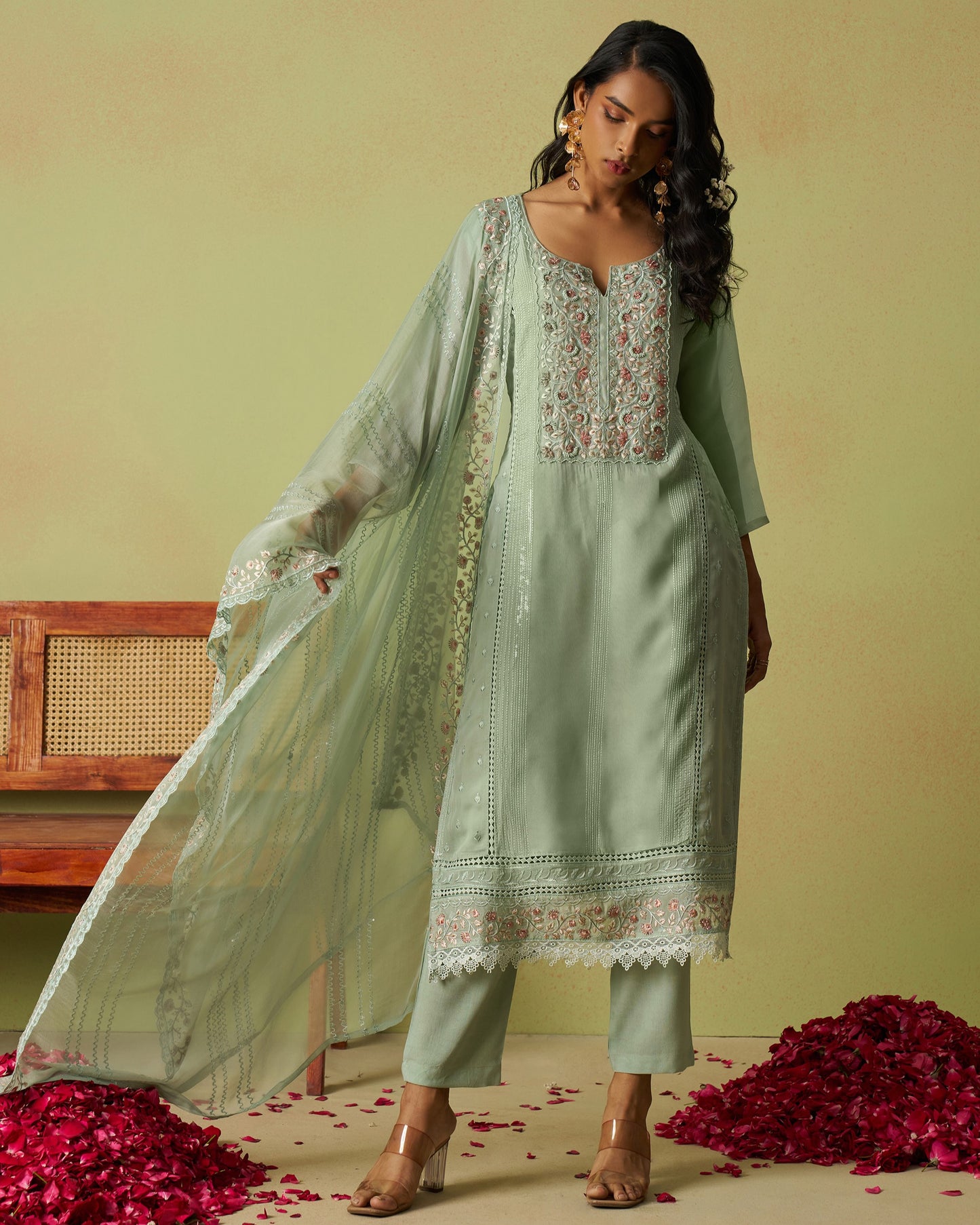 Woman wearing a light green embroidered outfit with a sheer dupatta on a yellow background