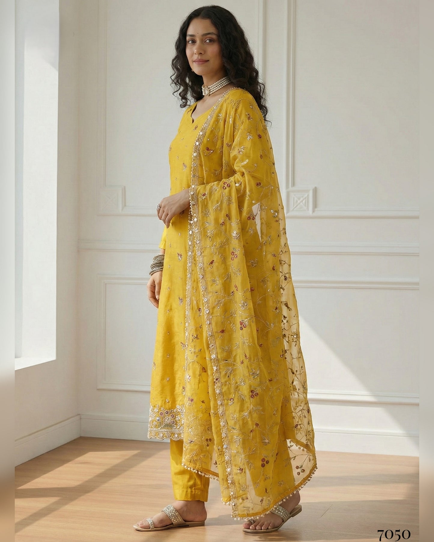 Woman wearing a yellow traditional outfit with a floral pattern in a well-lit room.