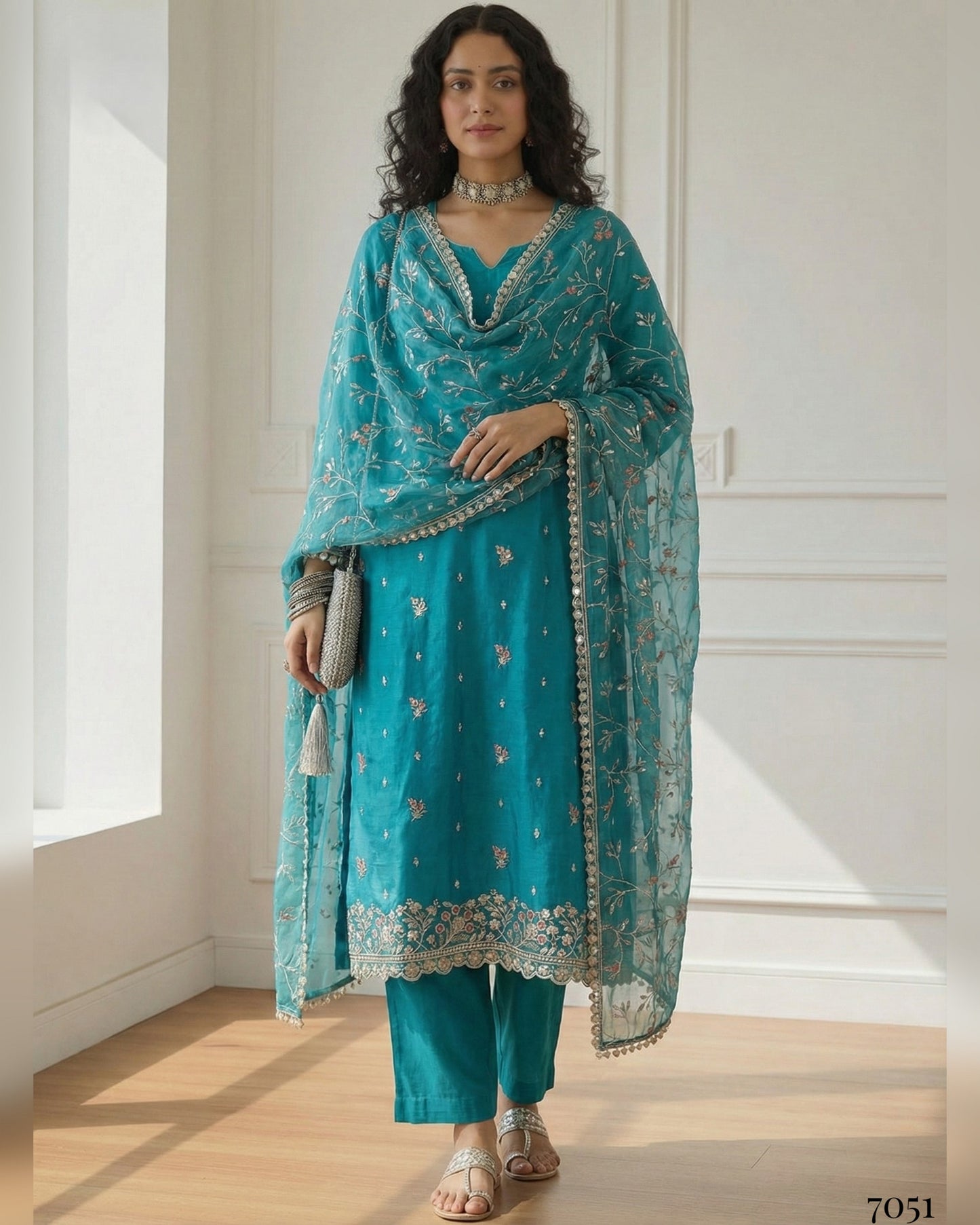 Woman wearing a teal traditional outfit with a matching dupatta in a bright room.