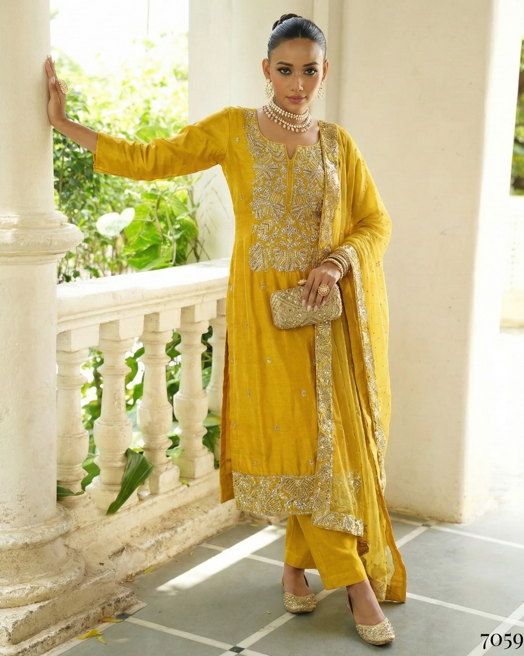 Woman in a yellow traditional outfit standing on a balcony with greenery in the background
