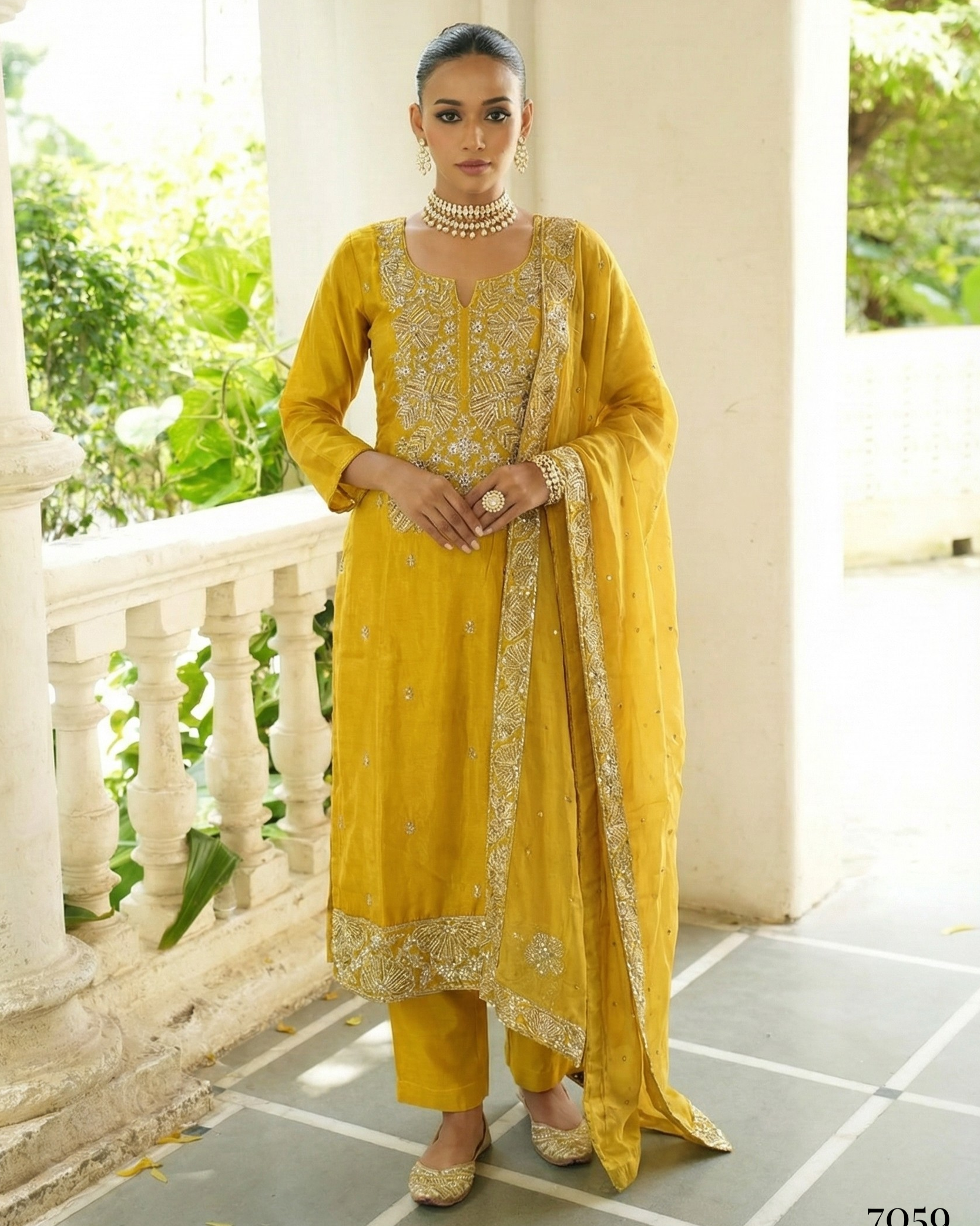 Woman in a yellow traditional outfit standing on a balcony with greenery in the background