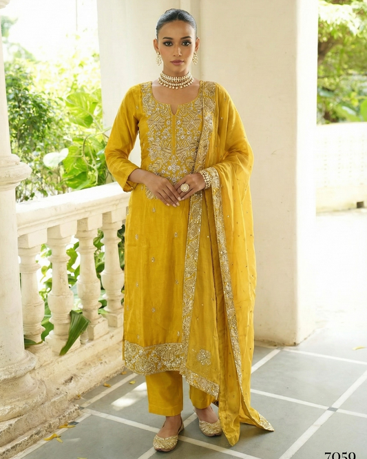 Woman in a yellow traditional outfit standing on a balcony with greenery in the background