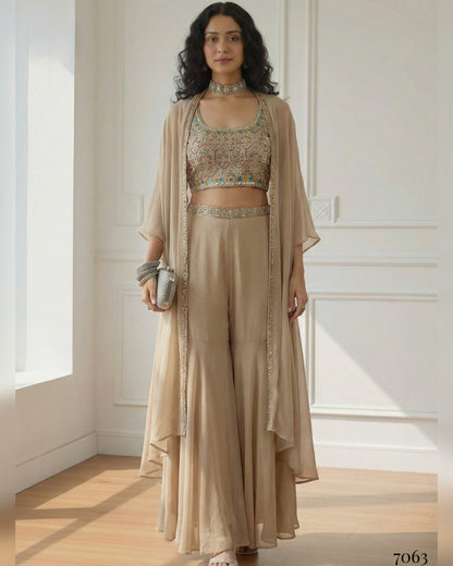 Woman wearing a beige traditional outfit with a matching jacket in a bright room.