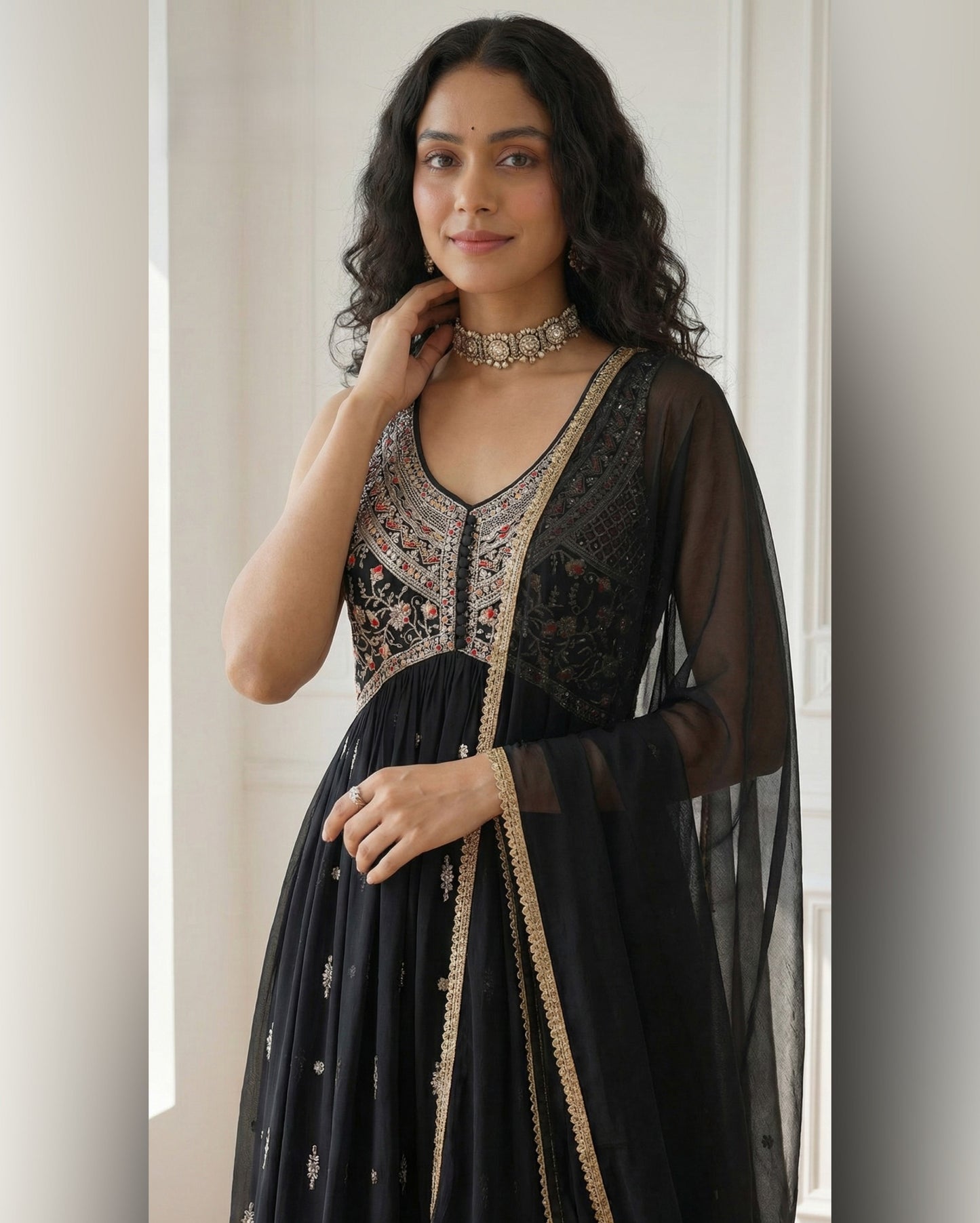 Woman wearing a black embroidered outfit with sheer sleeves against a neutral background