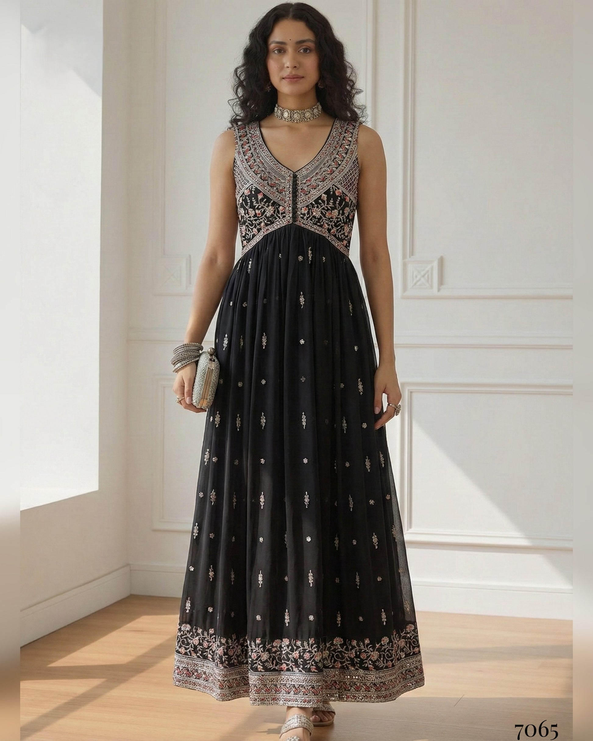 Woman wearing a black dress with intricate silver embroidery in a bright room.