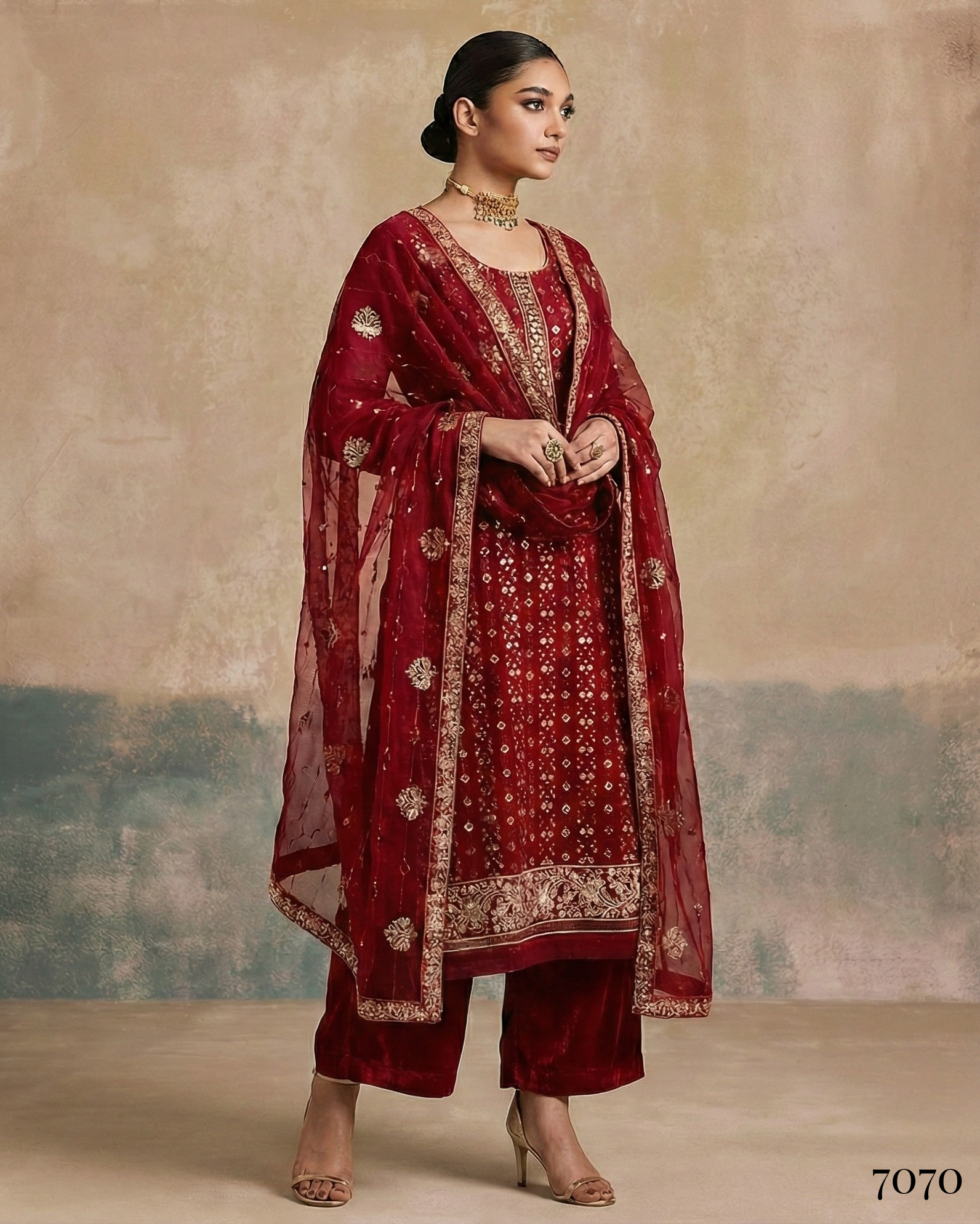 Woman wearing a traditional red outfit with gold embroidery against a textured beige background