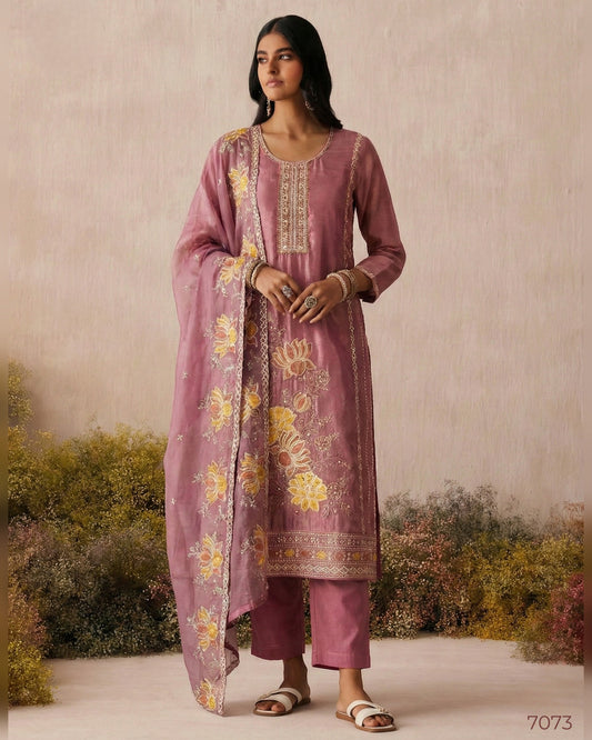 Woman wearing a pink embroidered traditional outfit with a scenic background