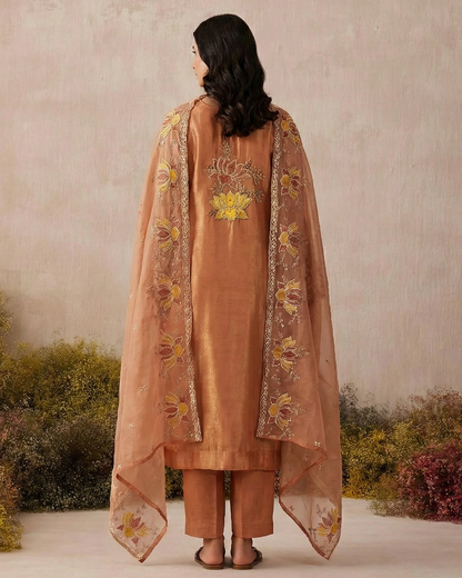 Woman wearing a peach-colored embroidered outfit with a matching dupatta against a neutral background.