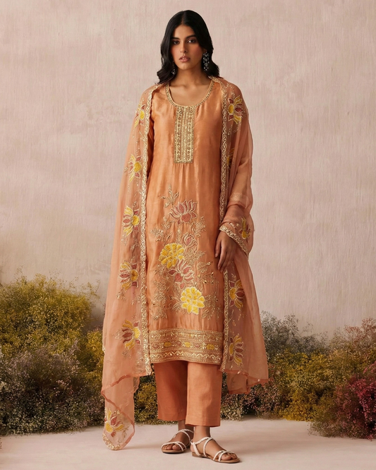Woman wearing a peach embroidered outfit with a natural background