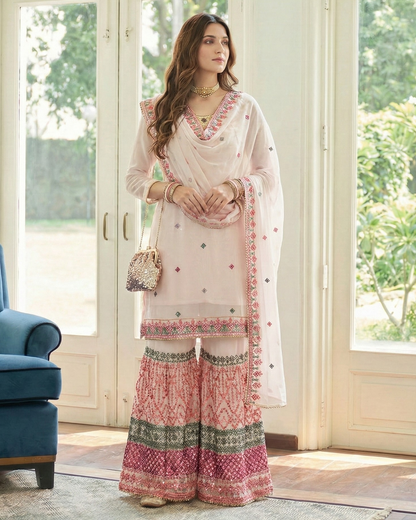 Woman in a traditional outfit standing in a room with large windows.