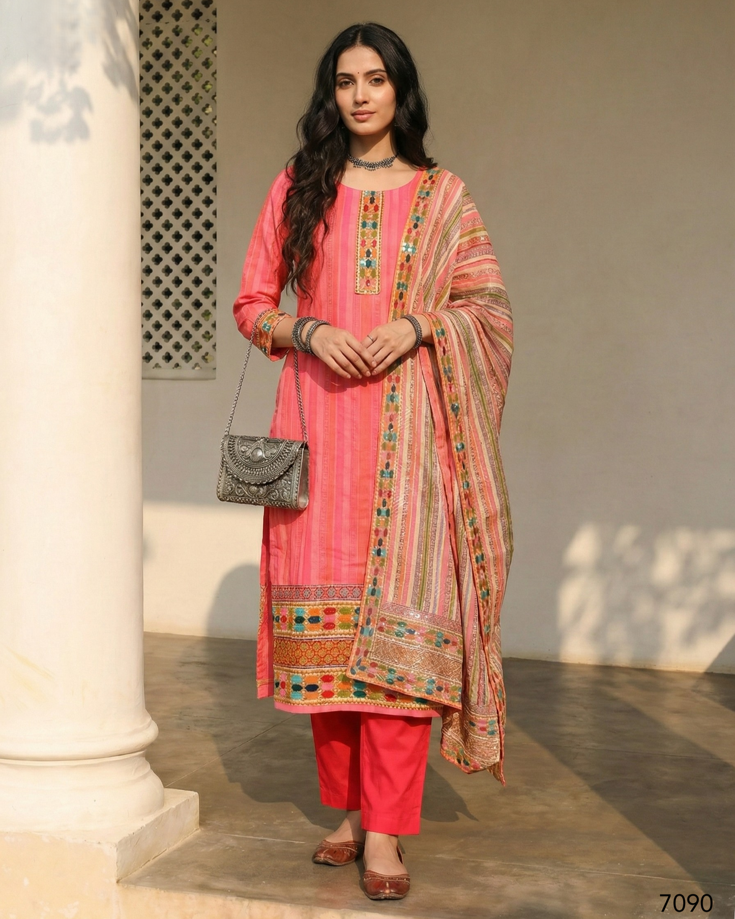 Woman in a pink traditional outfit with a patterned dupatta standing against a neutral background.