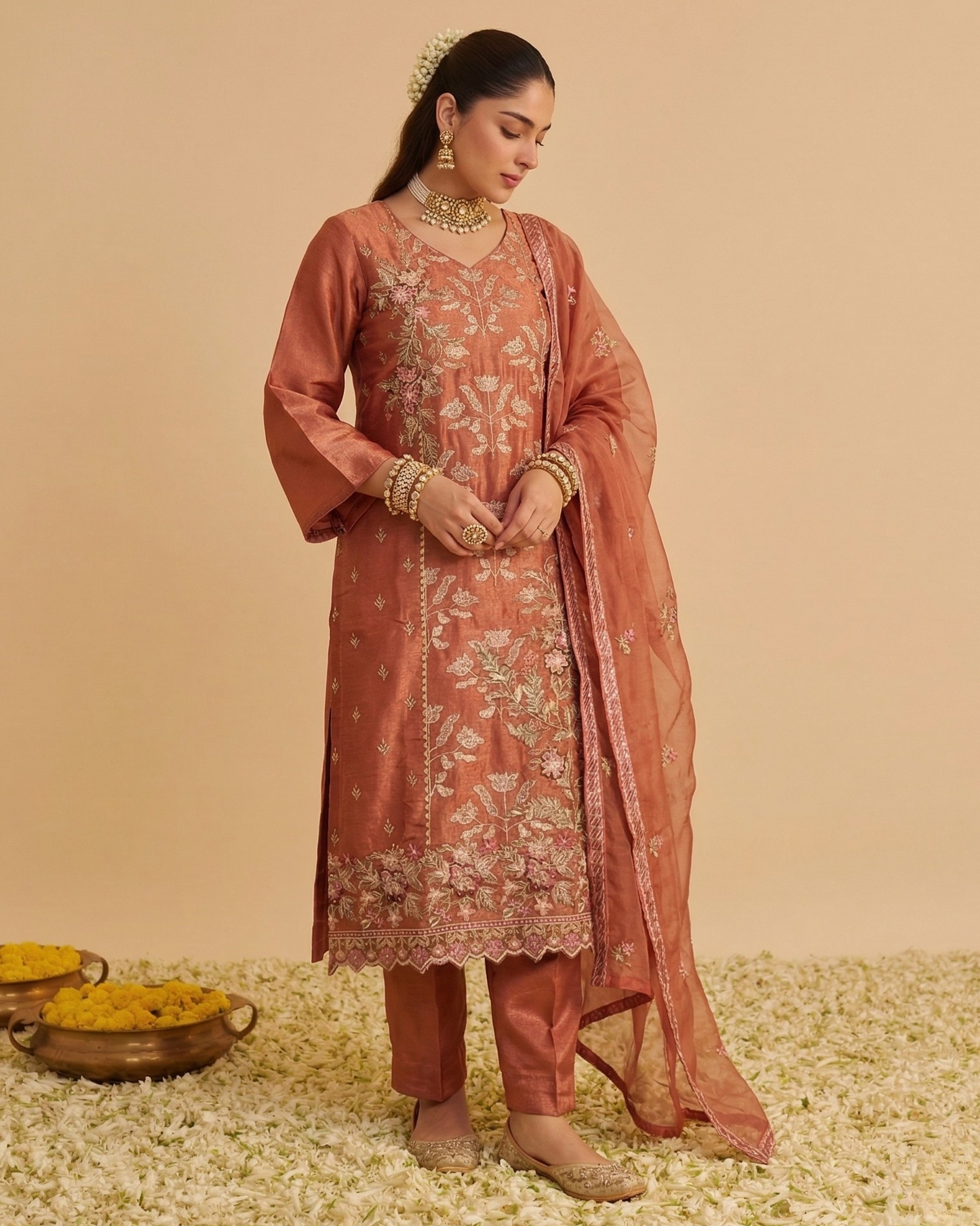Woman in traditional pink embroidered outfit with dupatta on a beige background