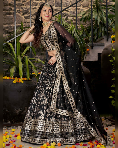 Woman in a black and silver traditional outfit with a stone wall and plants in the background
