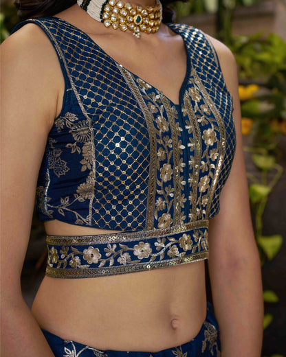 Blue embroidered blouse with gold detailing on a person, blurred background