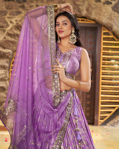 Woman in a purple saree with silver embroidery against a stone wall background