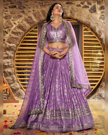Woman in a purple traditional outfit with silver details against a stone wall.
