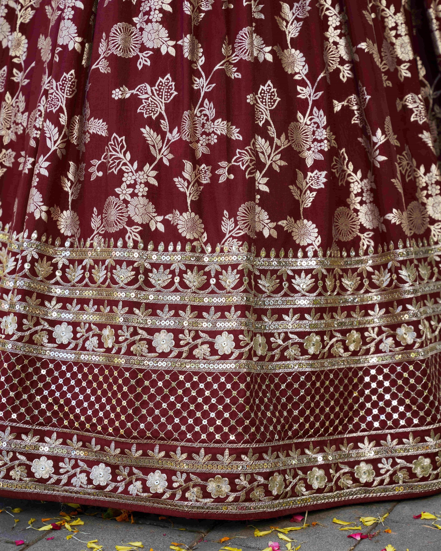 Maroon fabric with gold floral embroidery on a textured surface