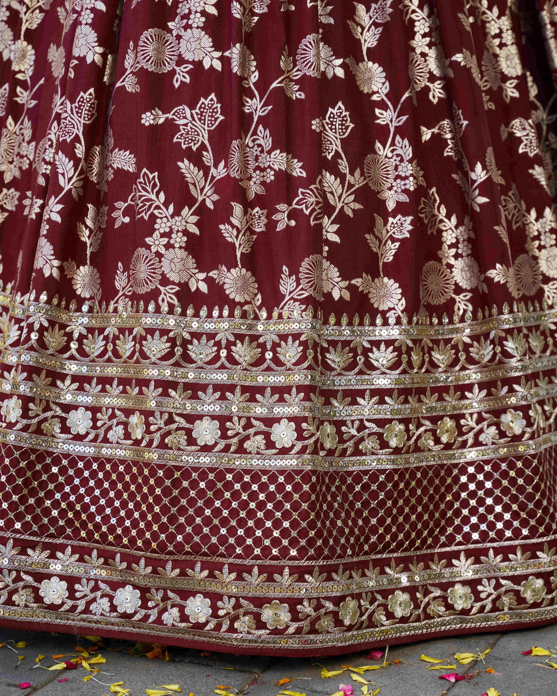 Maroon fabric with gold floral embroidery on a textured surface